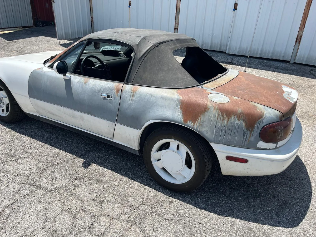 Classic Mazda Miata before restoration, with rust and primer patches
